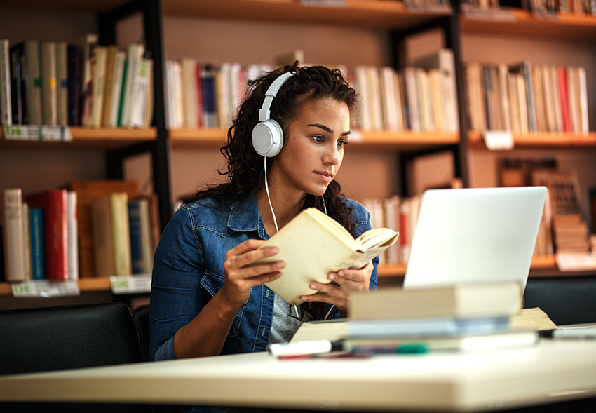 Young lady reading a book with headphones one